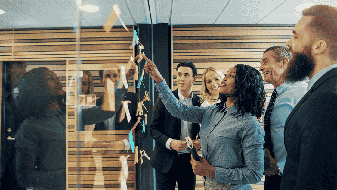 Team members stood around a meeting board