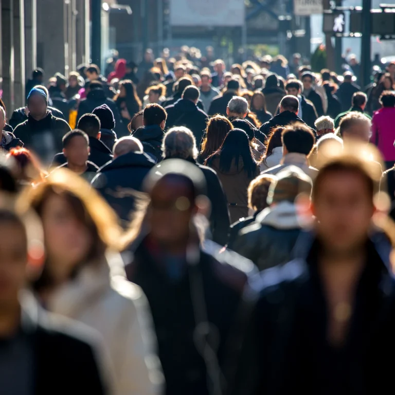 A large group of diverse people walking together down a busy street.