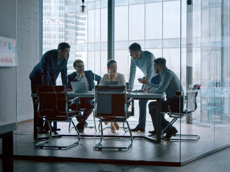 Business people collaborating in a modern office meeting, discussing ideas around a conference table.