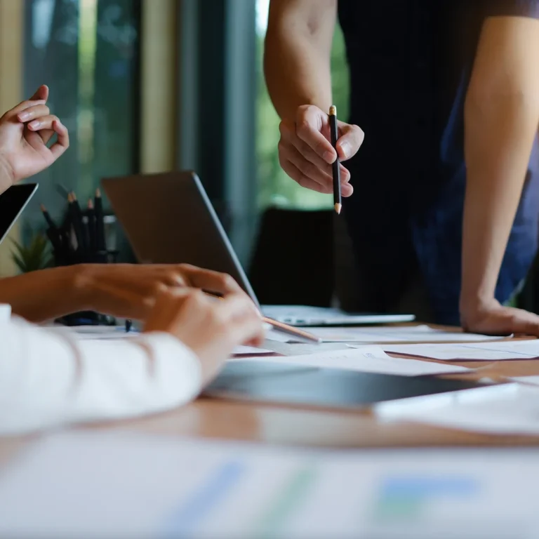 A couple of coworkers sitting around a table, using laptops and engaged in discussion.