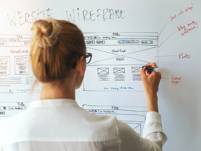 A woman writing on a whiteboard with a pen, focused and engaged in her task.