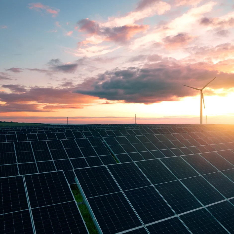 Solar panels and wind turbines silhouetted against a vibrant sunset sky, highlighting renewable energy sources.