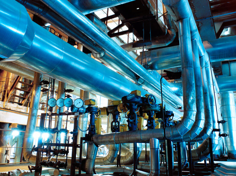 Pipes crisscrossing in a large industrial building, showcasing a complex network of plumbing and infrastructure.