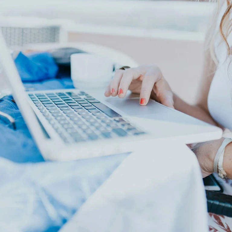 A woman sitting at a table, focused on her laptop.