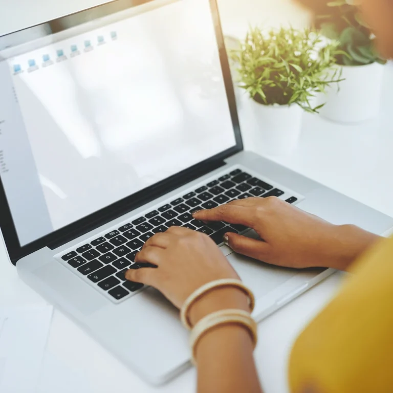 A woman is focused on typing on her laptop.