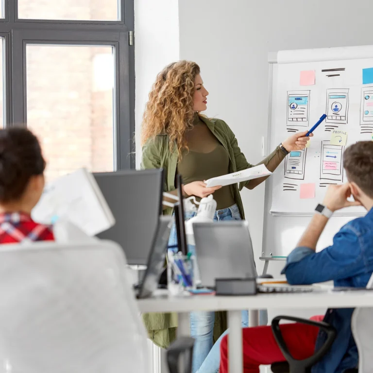 A woman presents to an engaged audience, sharing ideas and information in a professional setting.