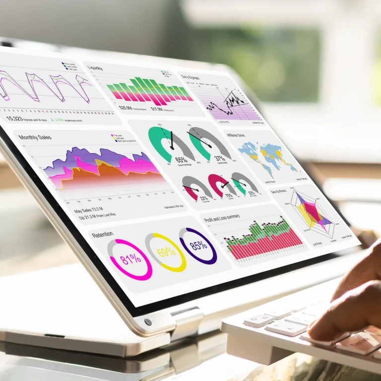 A person working on a laptop displaying a colorful graph, focused on data analysis.