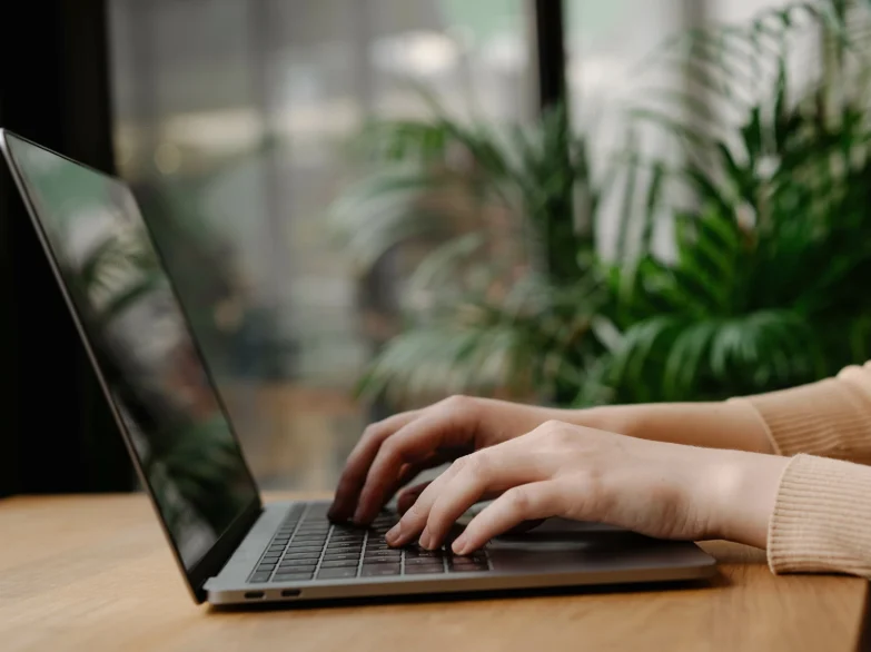 A person focused on typing on a laptop computer, with hands on the keyboard and a thoughtful expression.