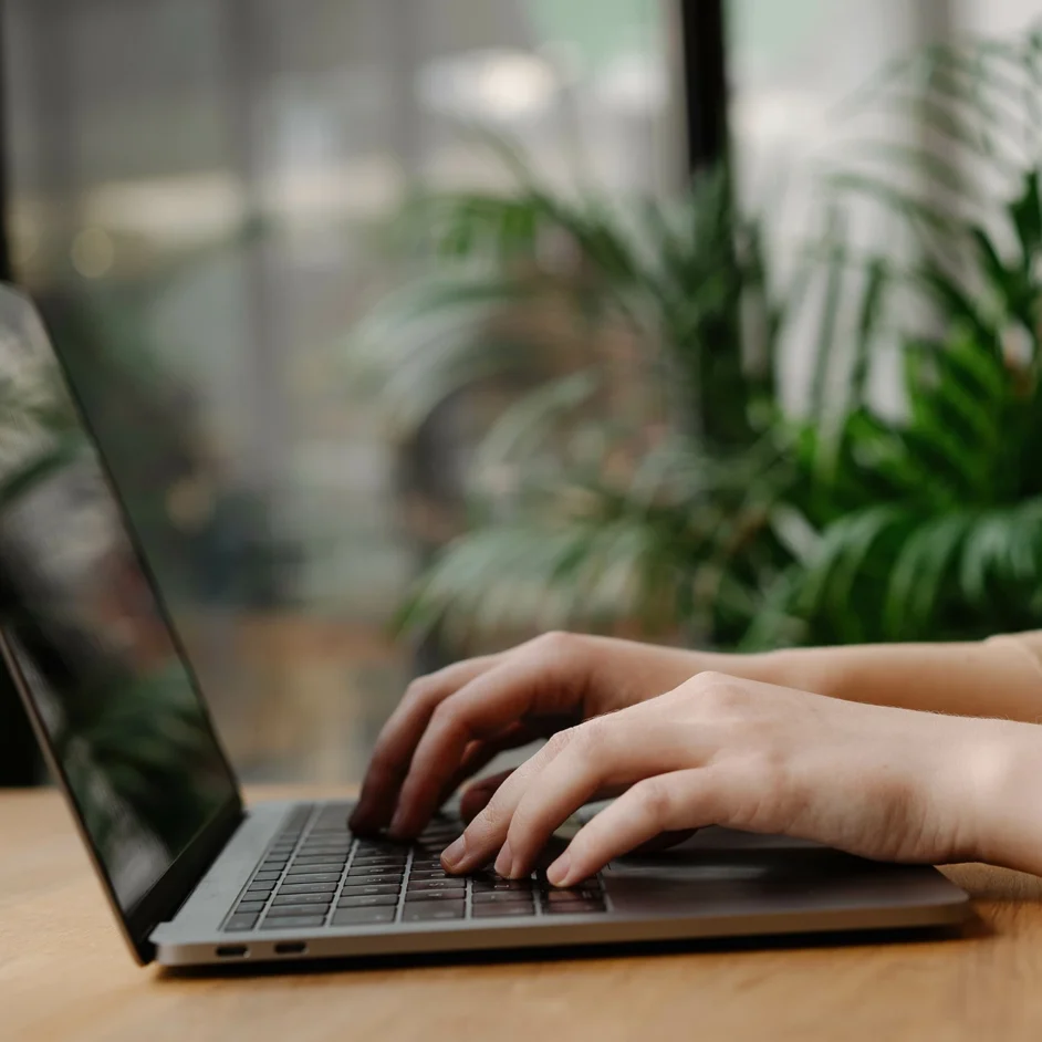 A person focused on typing on a laptop computer, with hands on the keyboard and a thoughtful expression.