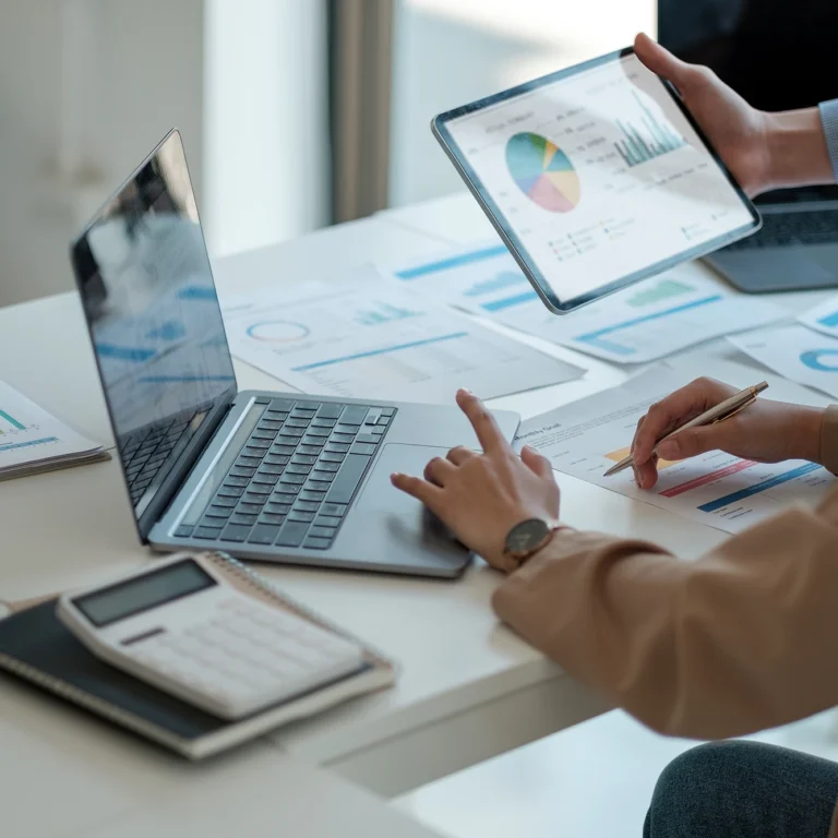 A man and woman collaborate on a laptop and tablet, focused on their work together.
