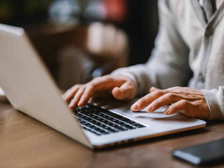 A person focused on typing on a laptop computer, with hands on the keyboard.