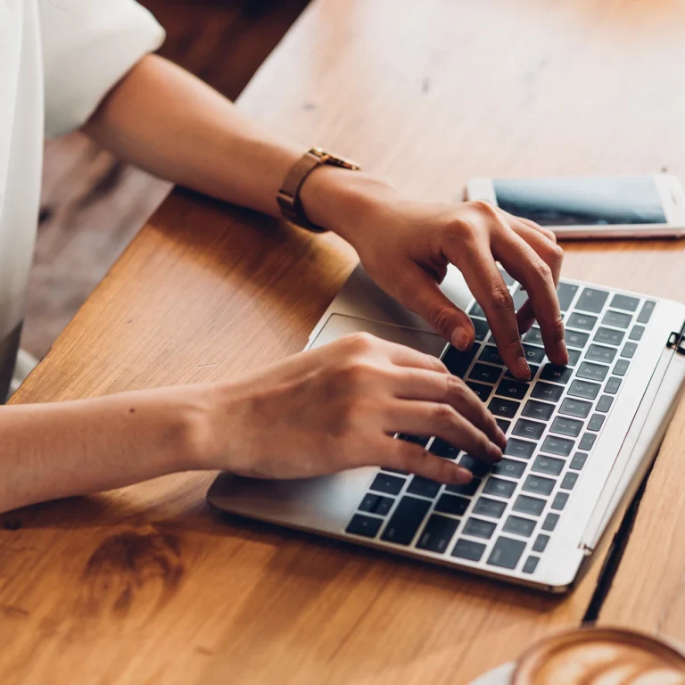 A woman focused on typing on a laptop while seated at a table.