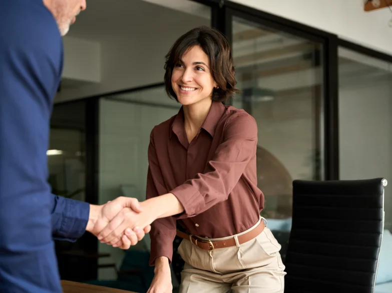 A woman and a man shake hands in a bright office, symbolising a successful business meeting or agreement.