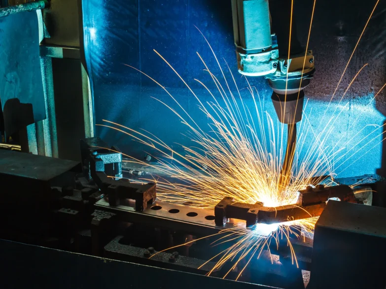 A welding machine is actively cutting through a piece of metal in a workshop setting.