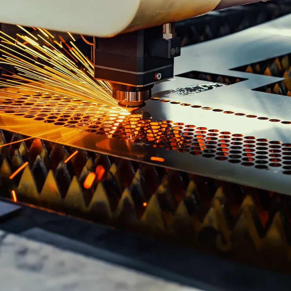 A laser cutter precisely cutting through a sheet of metal in a workshop setting.