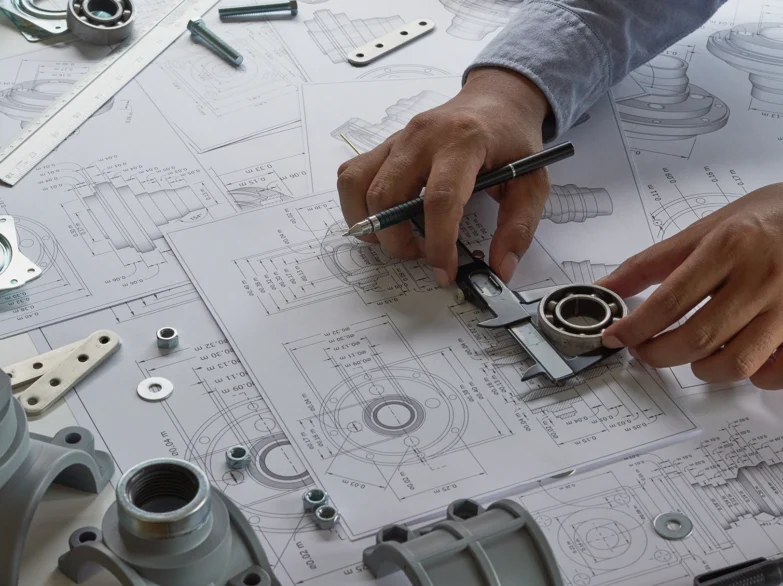 A person examines a blueprint while holding a wrench, focused on a mechanical project.