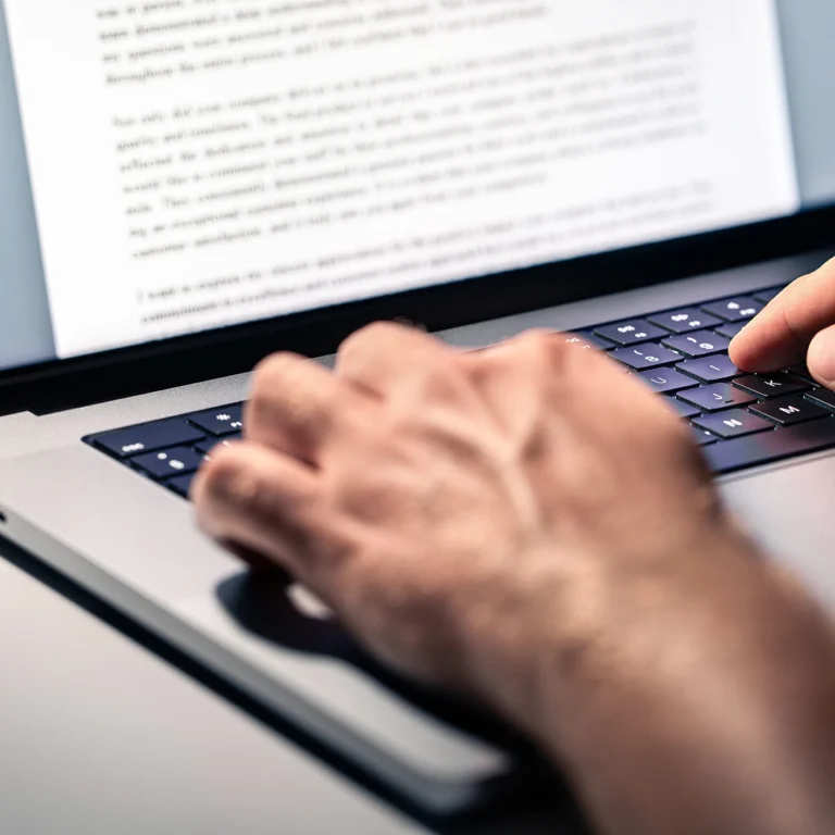 A person focused on typing on a laptop keyboard, with hands positioned over the keys.