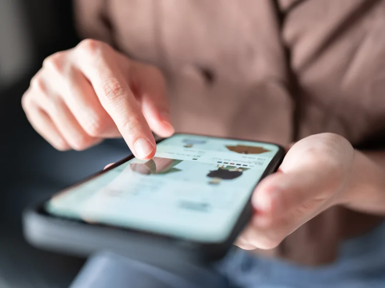 A person holding a smartphone displaying a digital menu, ready to order clothes.