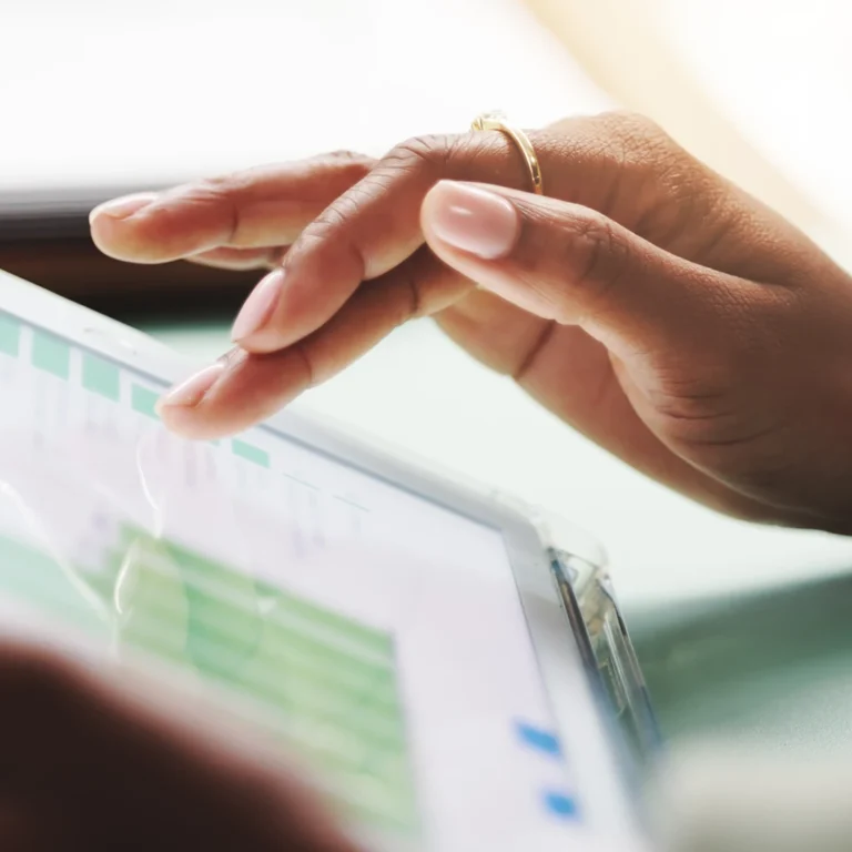 A person's hands are interacting with a tablet computer, browsing statistics.