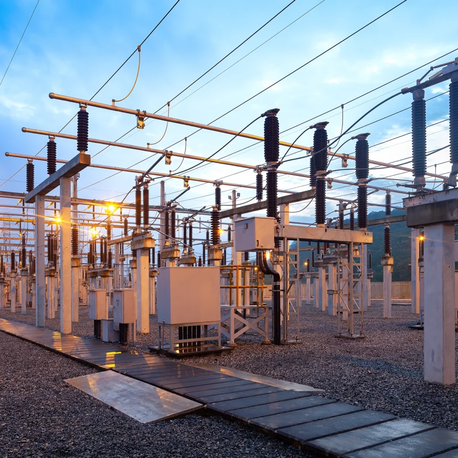 A large electrical substation featuring numerous wires and tall poles against a clear sky.
