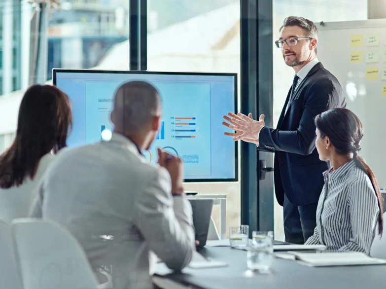 A man in a suit presents to an engaged audience, sharing ideas and insights during a professional meeting.