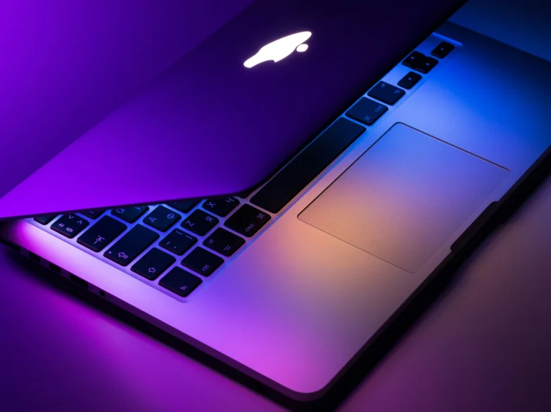 Stylised aeriel view of a MacBook laptop with cool purple lighting.