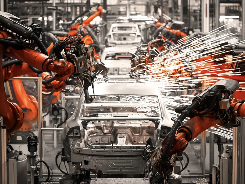 Image of robotic arms assembling car parts in a modern automotive factory, showcasing automation technology in action.