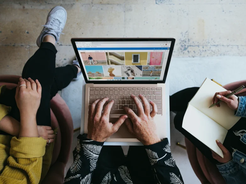 Three people sitting on a couch, focused on a laptop.