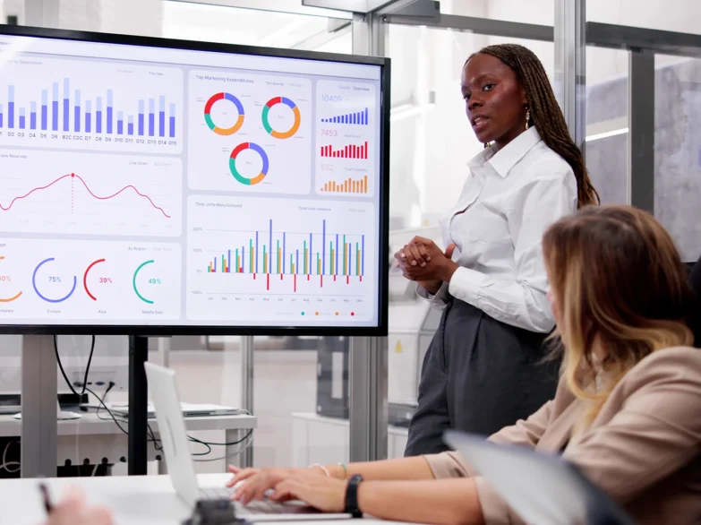 A woman presents to an engaged audience, sharing ideas and information in a professional setting.