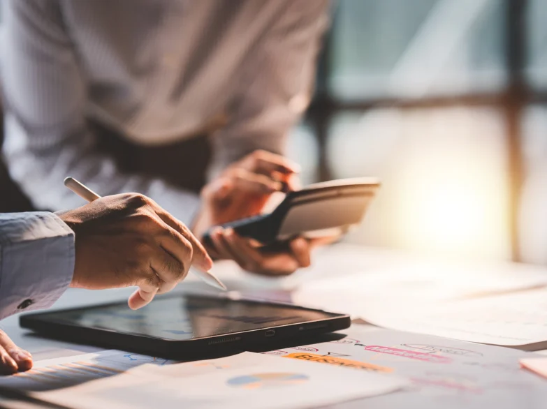 Business professionals collaborating on a laptop and tablet in a modern office setting.